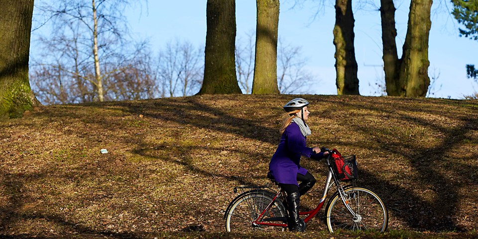 Kvinna på cykel i naturen. Foto.