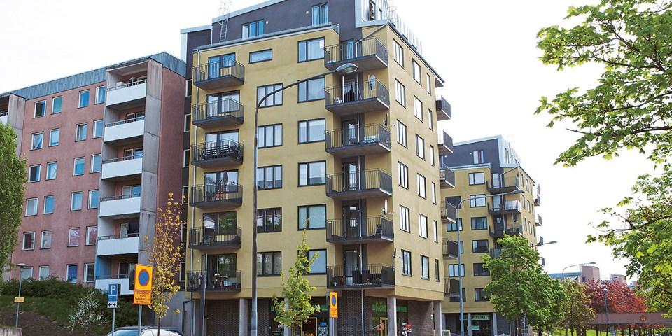 Två typiska lamellhus i sju våningar och separerad bil- och gångtrafik med gångbro över vägen i Spånga-Tensta.