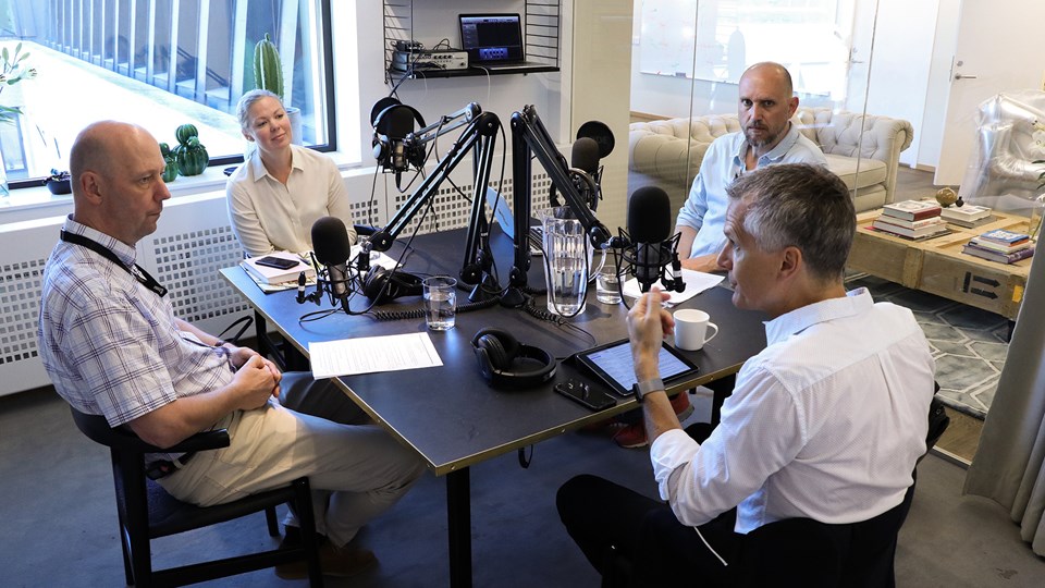 Tre män och en kvinna samtalar i en radiostudio.