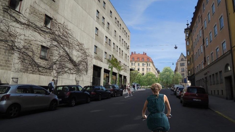 Rådmansgatan utmed högskolan med bilar parkerade utmed gatan. En cyklist som cyklar på vägen, fotomontage.
